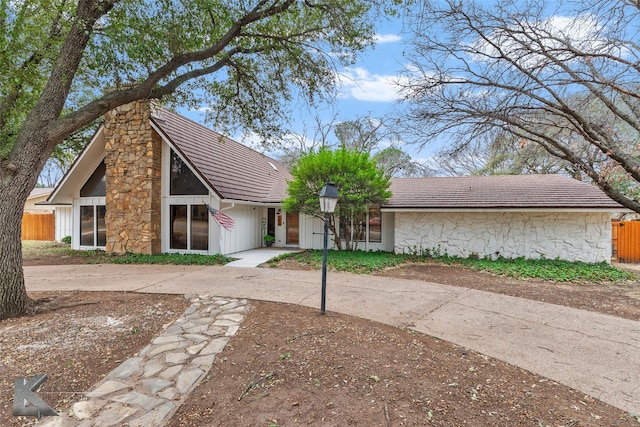 mid-century inspired home with a chimney and fence