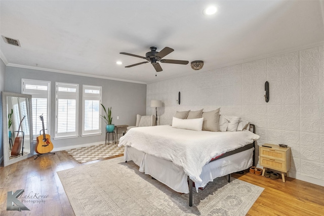 bedroom featuring light wood-style floors, baseboards, visible vents, and ornamental molding