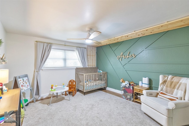 bedroom featuring ceiling fan, a crib, and baseboards