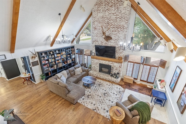 living room with vaulted ceiling with beams, a fireplace, an inviting chandelier, a textured ceiling, and wood finished floors