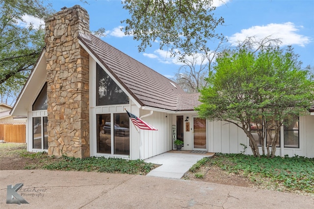 view of front of home featuring a chimney, board and batten siding, and fence