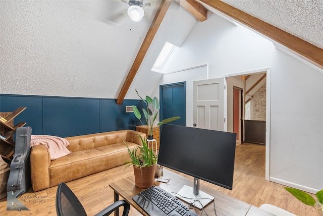 living room featuring lofted ceiling with skylight, a textured ceiling, light wood finished floors, and a ceiling fan