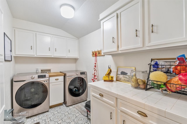 clothes washing area with a textured ceiling, washing machine and clothes dryer, and cabinet space