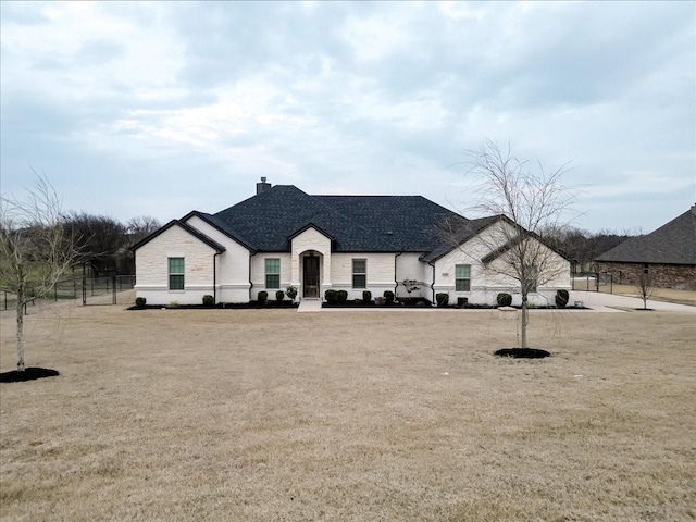 view of front of home featuring a chimney, fence, and roof with shingles