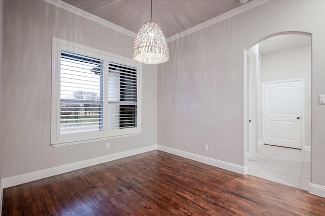 unfurnished room with baseboards, arched walkways, wood finished floors, crown molding, and a chandelier