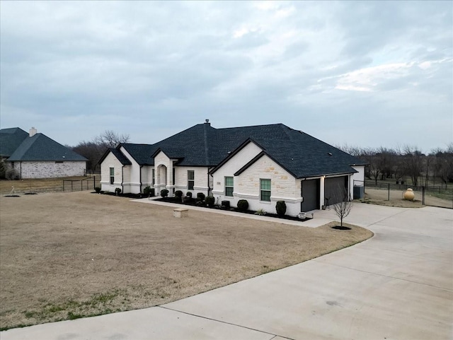 view of front of property featuring a garage, stone siding, fence, and concrete driveway