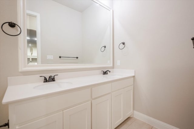 bathroom with double vanity, tile patterned flooring, a sink, and baseboards