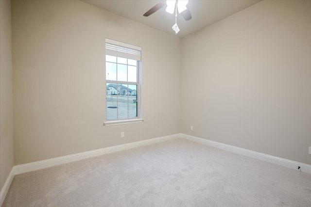 spare room featuring light colored carpet, ceiling fan, and baseboards