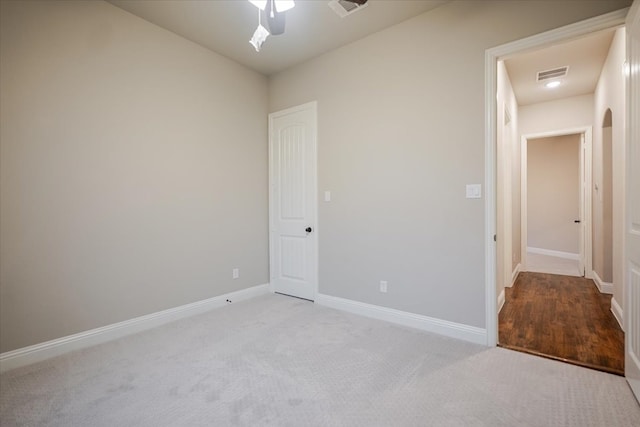 unfurnished bedroom with baseboards, visible vents, arched walkways, ceiling fan, and carpet