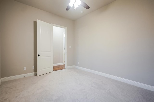 spare room with light carpet, baseboards, and a ceiling fan