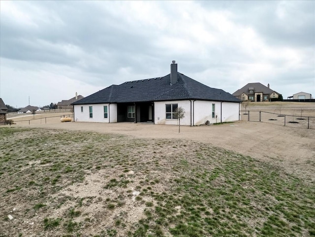 rear view of property featuring a chimney and fence