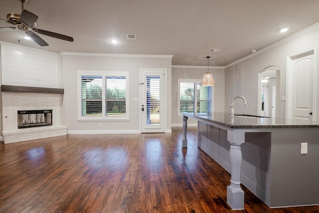 kitchen featuring ornamental molding, dark stone counters, visible vents, and a sink