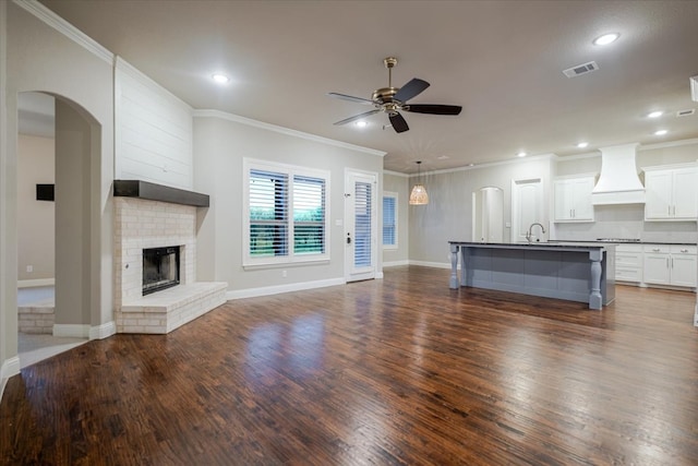 unfurnished living room with a fireplace, visible vents, dark wood finished floors, and a ceiling fan