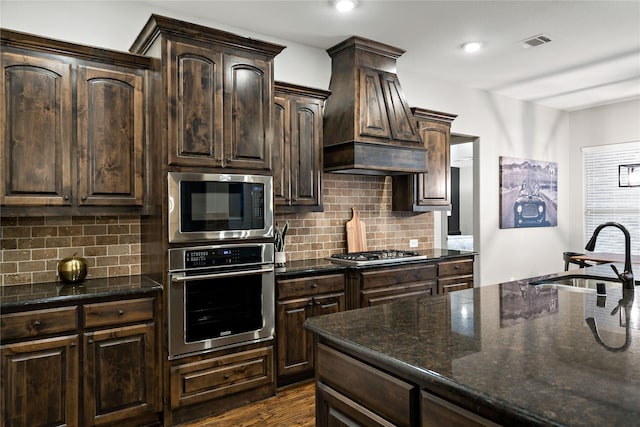 kitchen with dark brown cabinets, visible vents, stainless steel appliances, and a sink