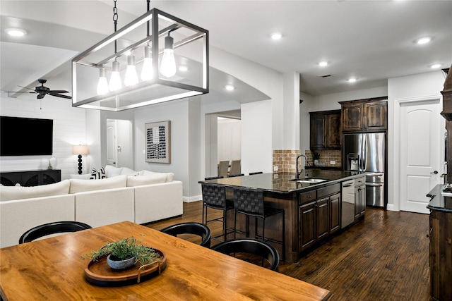 kitchen with open floor plan, dark brown cabinets, appliances with stainless steel finishes, and a sink