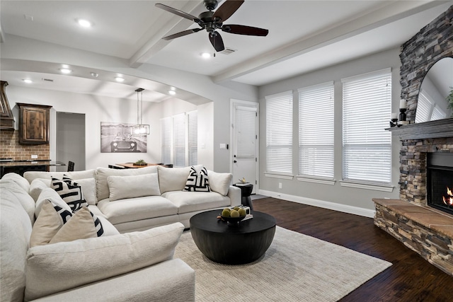 living room with a stone fireplace, recessed lighting, baseboards, dark wood-style floors, and beamed ceiling