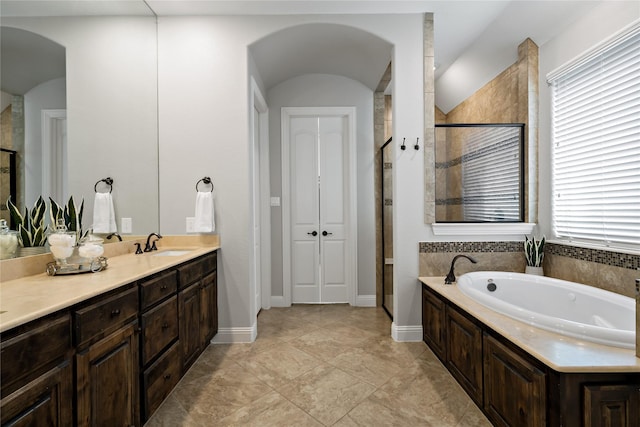 bathroom featuring a stall shower, baseboards, a bath, and vanity