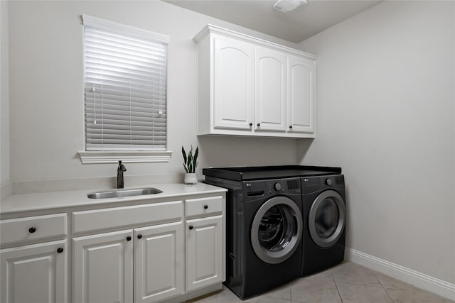 washroom featuring light tile patterned flooring, a sink, baseboards, cabinet space, and washing machine and clothes dryer