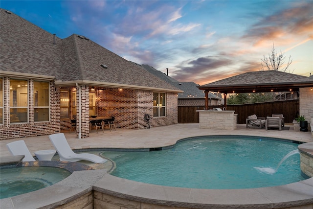 pool at dusk with a patio area, fence, an outdoor living space, and an in ground hot tub