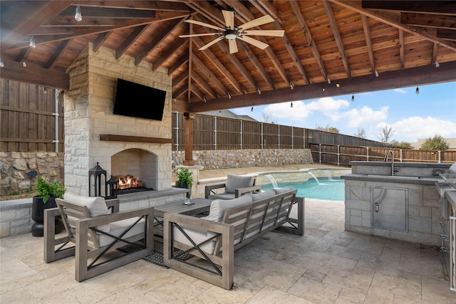 view of pool featuring an outdoor stone fireplace, area for grilling, a patio area, a sink, and a fenced backyard