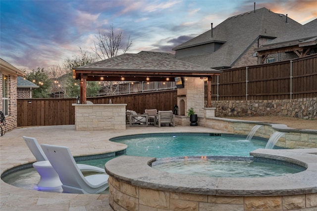 pool at dusk featuring a gazebo, a patio area, a fenced backyard, and a pool with connected hot tub