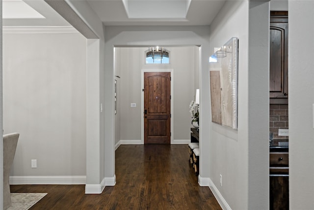 entrance foyer with dark wood-style floors, a notable chandelier, and baseboards