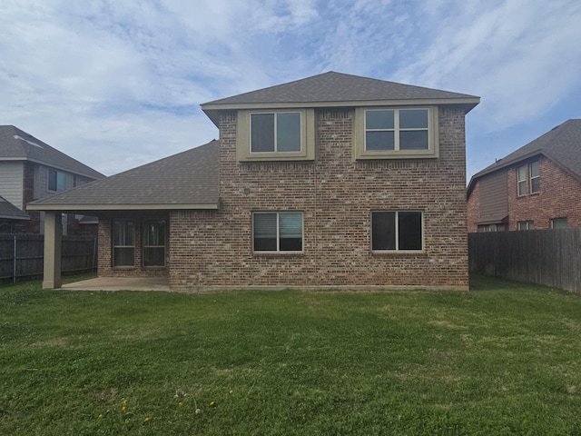 rear view of property with a yard, a patio, and brick siding