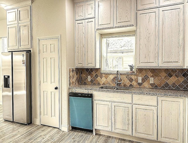 kitchen featuring a sink, light wood-style floors, decorative backsplash, dishwasher, and stainless steel fridge