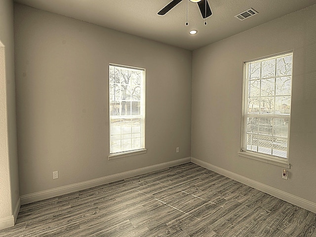 spare room with baseboards, visible vents, and wood finished floors