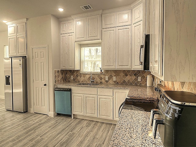 kitchen with visible vents, light wood-style flooring, decorative backsplash, appliances with stainless steel finishes, and a sink