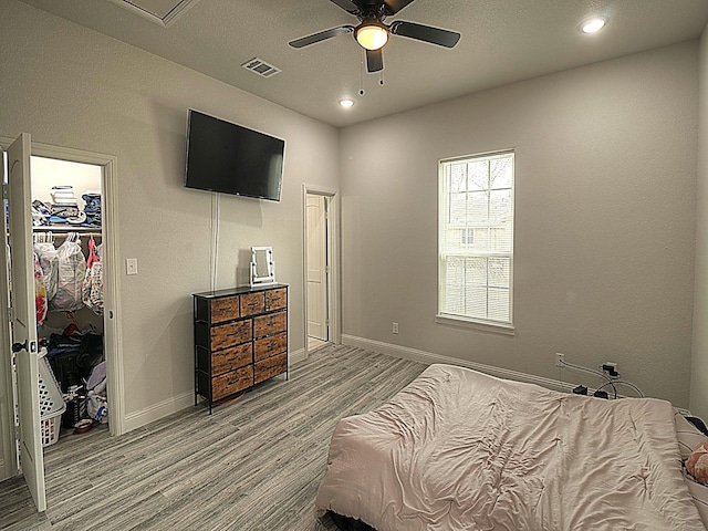 bedroom featuring baseboards, a spacious closet, visible vents, and wood finished floors