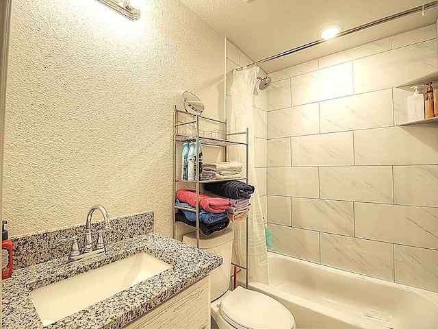 full bathroom featuring toilet, shower / bath combo, vanity, and a textured wall