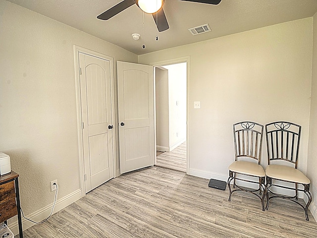 living area featuring light wood finished floors, baseboards, visible vents, and a ceiling fan