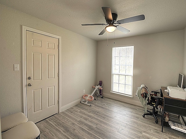 office with a textured wall, ceiling fan, a textured ceiling, wood finished floors, and baseboards