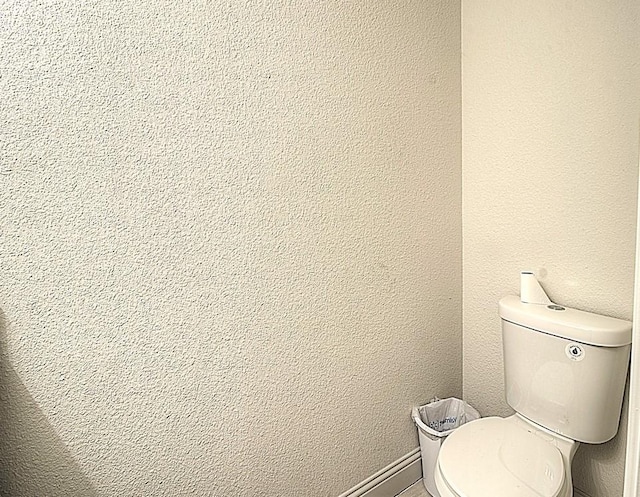 bathroom featuring a textured wall and toilet