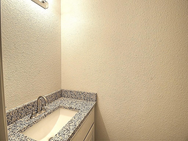 bathroom featuring a textured wall and vanity