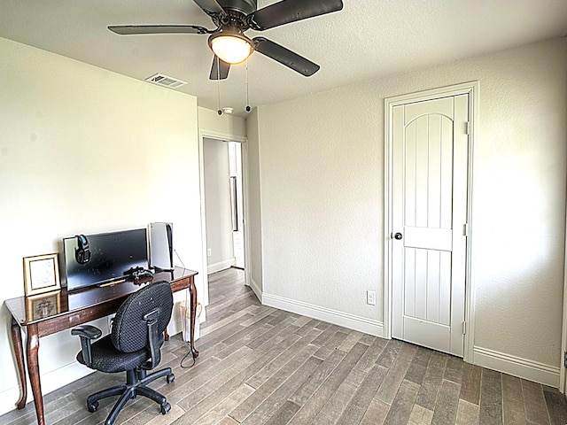 office space featuring a ceiling fan, visible vents, baseboards, and wood finished floors