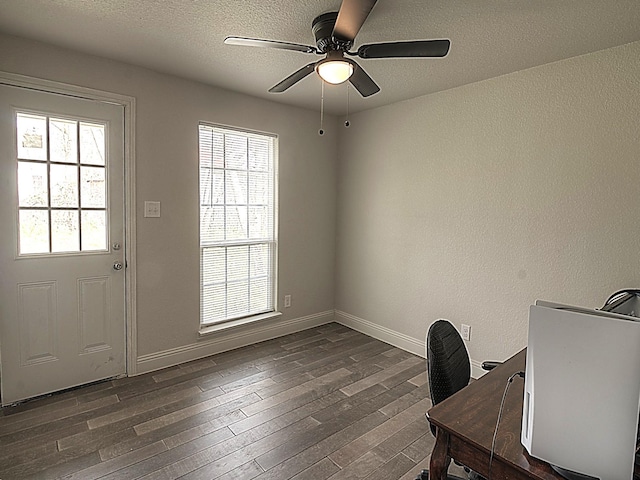 unfurnished office featuring dark wood-style floors, ceiling fan, baseboards, and a textured ceiling