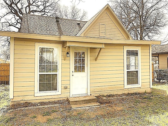 exterior space featuring fence and roof with shingles