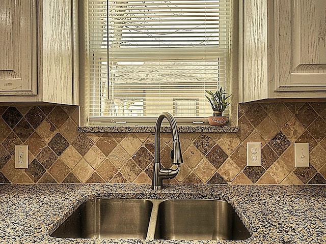 kitchen featuring dark countertops, cream cabinetry, a sink, and decorative backsplash