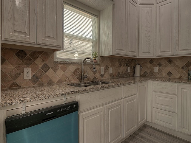 kitchen featuring dishwasher, light stone counters, a sink, and decorative backsplash