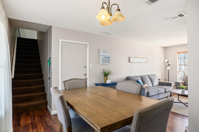 dining space with visible vents, dark wood finished floors, stairway, and a textured ceiling