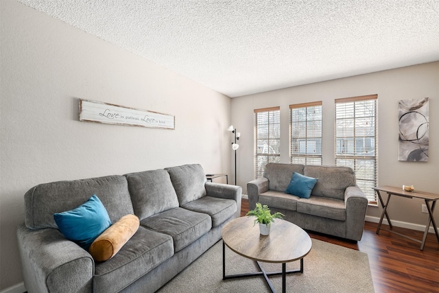 living room with a textured ceiling, wood finished floors, and baseboards