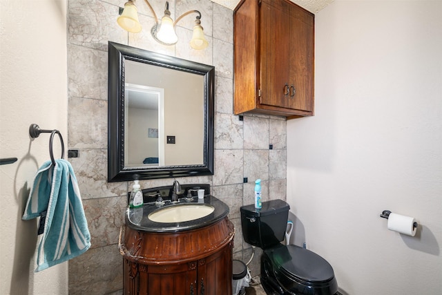 half bathroom featuring toilet, vanity, and tile walls