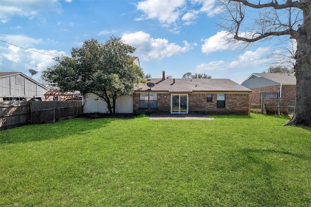 back of property with brick siding, a lawn, and a fenced backyard