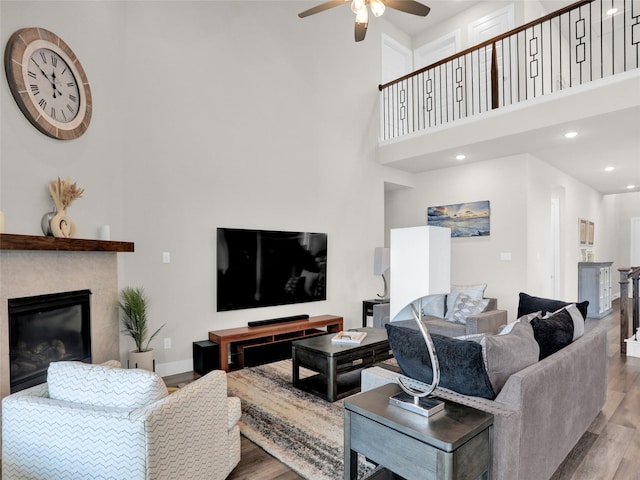 living room with ceiling fan, recessed lighting, wood finished floors, baseboards, and a glass covered fireplace