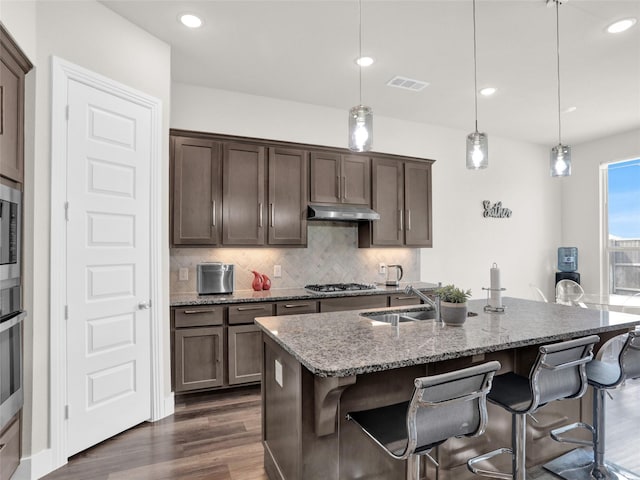 kitchen with tasteful backsplash, visible vents, dark wood-style floors, appliances with stainless steel finishes, and under cabinet range hood