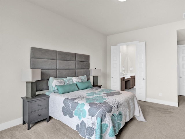 bedroom featuring light carpet, baseboards, and ensuite bathroom