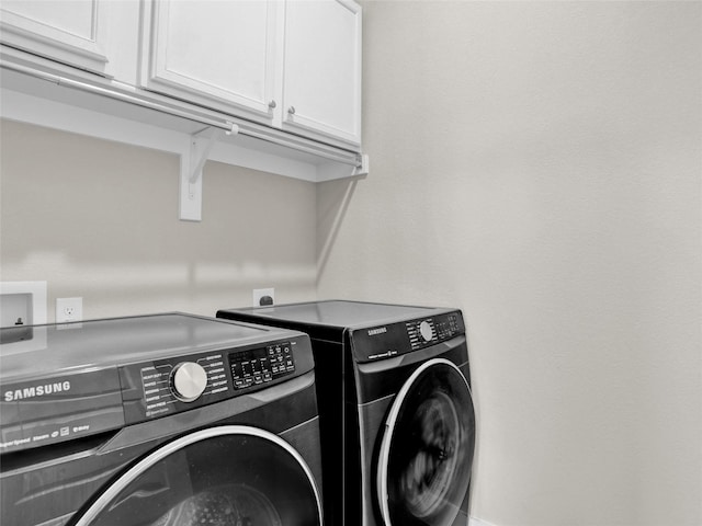 laundry area with independent washer and dryer and cabinet space