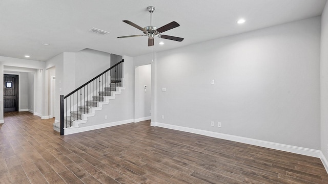 unfurnished room with dark wood-type flooring, visible vents, baseboards, and stairs